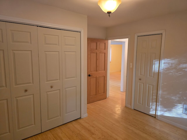 unfurnished bedroom featuring two closets and light hardwood / wood-style flooring