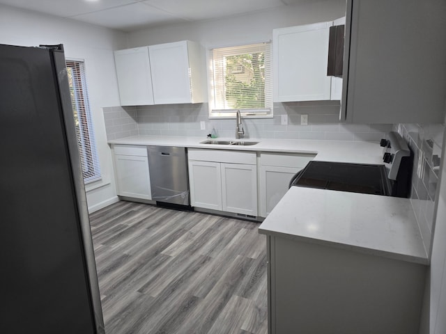 kitchen featuring backsplash, white cabinets, sink, light hardwood / wood-style flooring, and stainless steel appliances