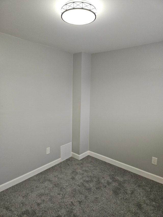 spare room with dark carpet