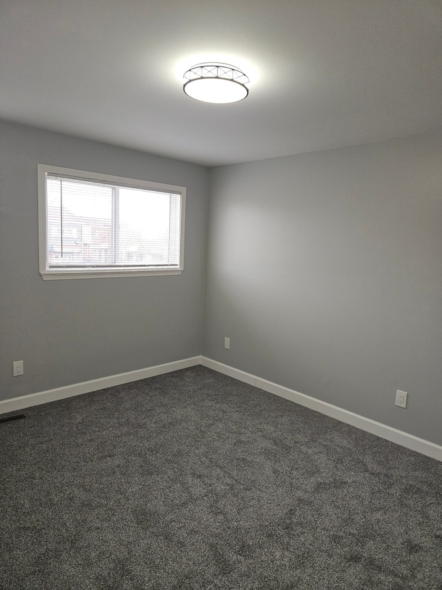 unfurnished room with dark carpet