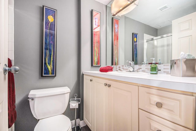 bathroom with vanity, toilet, decorative backsplash, and walk in shower