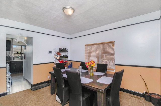 dining area featuring light carpet and a textured ceiling