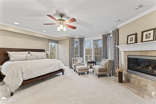 carpeted bedroom featuring ceiling fan, crown molding, and a tiled fireplace