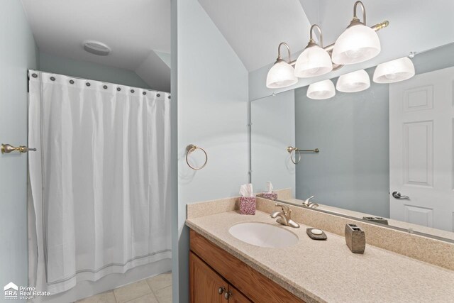 bathroom with vanity, vaulted ceiling, and tile patterned floors