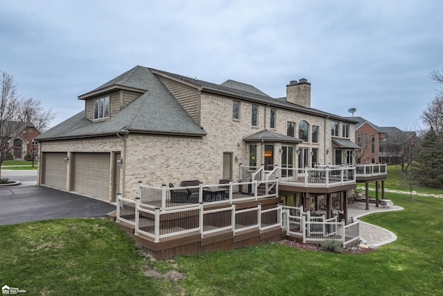 back of property featuring a garage, a lawn, and a wooden deck