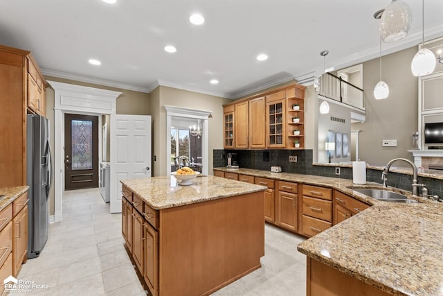 kitchen with sink, a center island, stainless steel fridge with ice dispenser, light stone counters, and pendant lighting