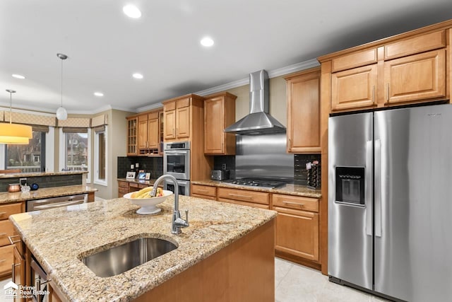 kitchen featuring light stone countertops, stainless steel appliances, wall chimney range hood, tasteful backsplash, and a kitchen island with sink