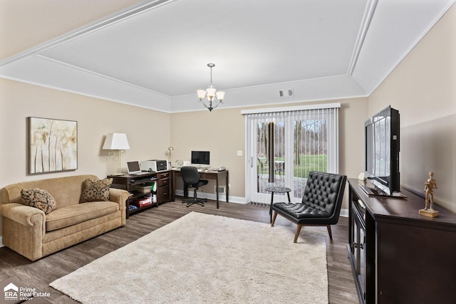 living room with a raised ceiling, dark hardwood / wood-style flooring, ornamental molding, and a notable chandelier