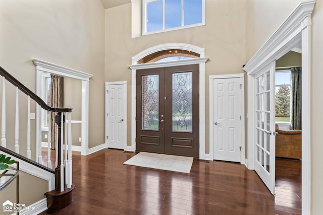 entrance foyer with a towering ceiling, dark wood-type flooring, and french doors