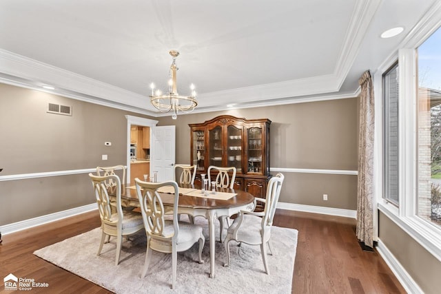 dining room featuring a notable chandelier, dark hardwood / wood-style floors, ornamental molding, and a tray ceiling