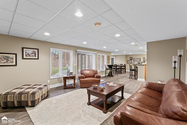 living room with hardwood / wood-style floors and a paneled ceiling