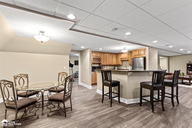 kitchen with a kitchen breakfast bar, stainless steel fridge, sink, and dark hardwood / wood-style floors