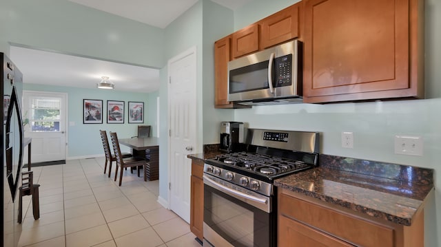 kitchen with dark stone countertops, light tile patterned floors, and appliances with stainless steel finishes