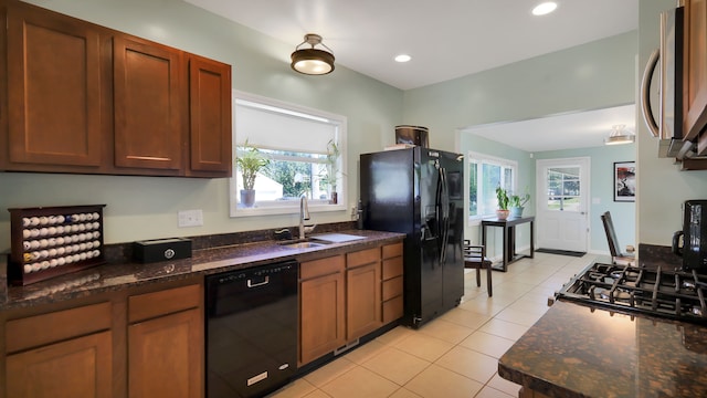 kitchen with sink, plenty of natural light, dark stone countertops, and black appliances