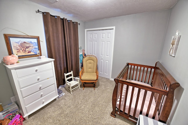 bedroom with a closet, a nursery area, a textured ceiling, and carpet flooring