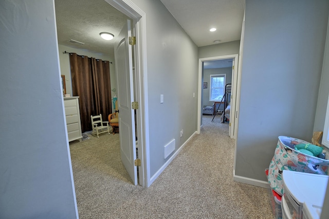 hall featuring light colored carpet and a textured ceiling