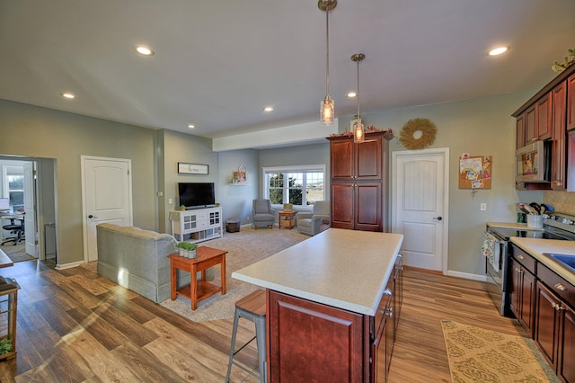 kitchen with a center island, hardwood / wood-style flooring, a kitchen breakfast bar, pendant lighting, and stainless steel appliances