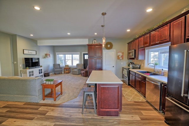 kitchen featuring appliances with stainless steel finishes, pendant lighting, sink, a kitchen breakfast bar, and a center island