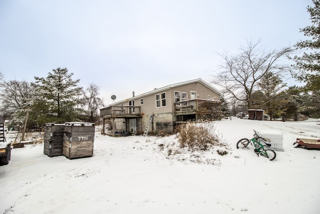 snow covered back of property featuring a wooden deck