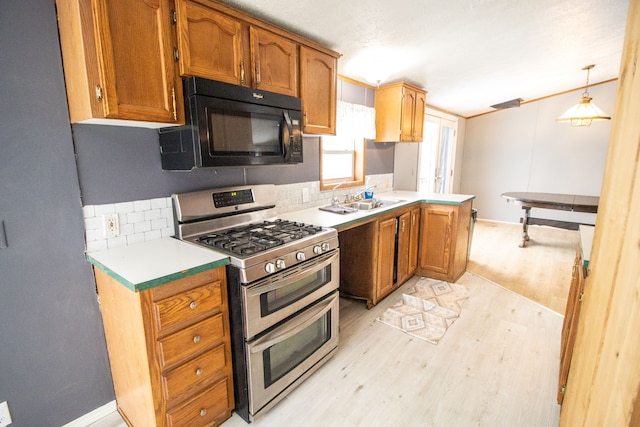 kitchen featuring pendant lighting, sink, range with two ovens, kitchen peninsula, and light hardwood / wood-style flooring