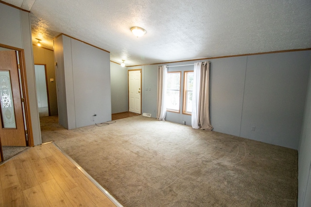 spare room featuring light carpet and a textured ceiling