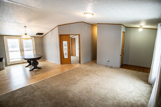 carpeted entrance foyer with lofted ceiling, crown molding, french doors, and a textured ceiling