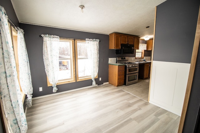 kitchen featuring light hardwood / wood-style floors, range with two ovens, and a textured ceiling