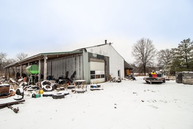 view of snow covered exterior featuring a garage and an outdoor structure