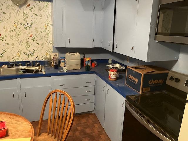 kitchen with white cabinetry, dark parquet floors, sink, and electric range oven