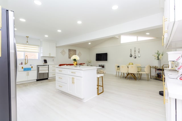 kitchen featuring appliances with stainless steel finishes, a center island, white cabinetry, and vaulted ceiling with beams