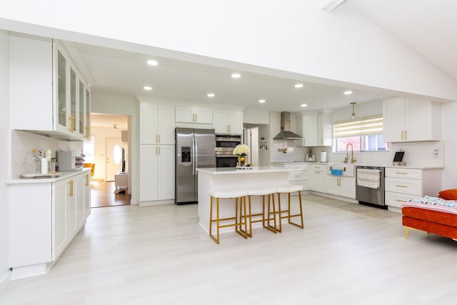 kitchen with white cabinets, wall chimney exhaust hood, a center island, and appliances with stainless steel finishes