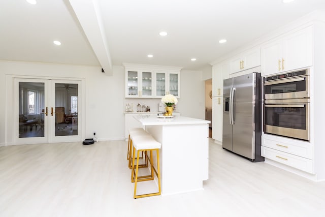 kitchen featuring a center island, white cabinets, beam ceiling, a kitchen bar, and stainless steel appliances