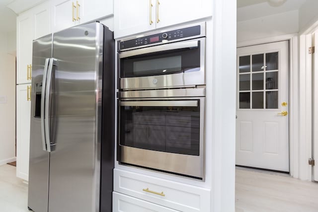 kitchen featuring light wood-type flooring, stainless steel appliances, and white cabinetry