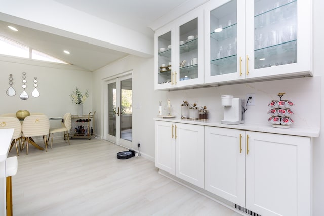 bar featuring white cabinets, lofted ceiling, and light wood-type flooring