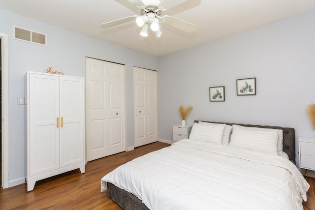 bedroom featuring hardwood / wood-style floors, ceiling fan, and two closets