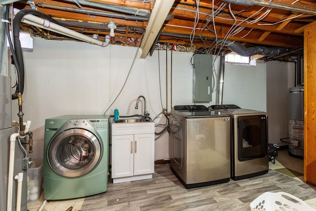 clothes washing area featuring cabinets, electric panel, light hardwood / wood-style flooring, water heater, and washing machine and clothes dryer