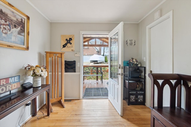 doorway to outside with light hardwood / wood-style flooring and crown molding