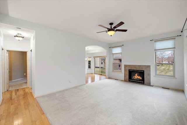 unfurnished living room featuring a fireplace, light hardwood / wood-style floors, and ceiling fan