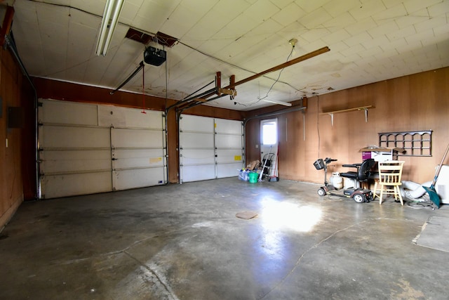 garage featuring a garage door opener and wooden walls