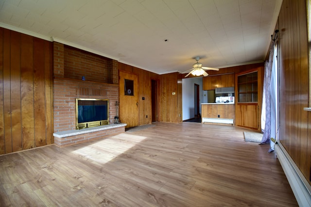 unfurnished living room with light hardwood / wood-style flooring, a baseboard heating unit, and wood walls