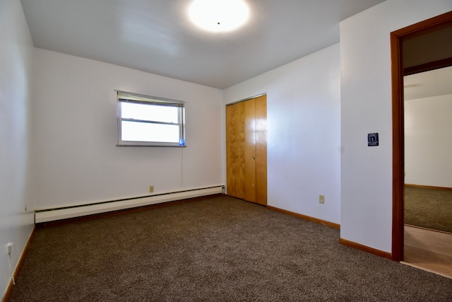 unfurnished bedroom with a closet, dark carpet, and a baseboard heating unit