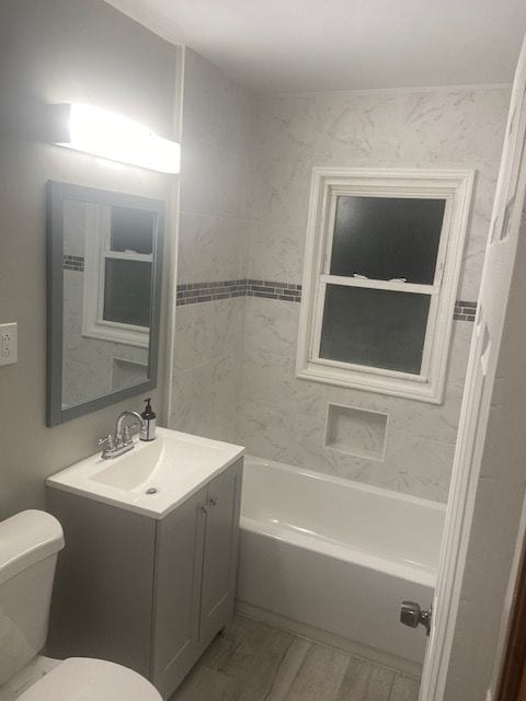 full bathroom featuring tiled shower / bath combo, toilet, and vanity