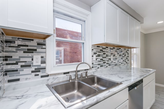 kitchen with sink, white cabinets, backsplash, stainless steel dishwasher, and light stone counters