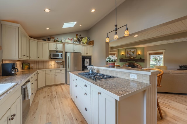 kitchen with a kitchen island, appliances with stainless steel finishes, a kitchen breakfast bar, decorative backsplash, and hanging light fixtures