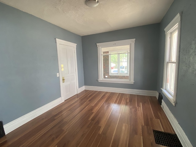 empty room with a textured ceiling and dark hardwood / wood-style floors