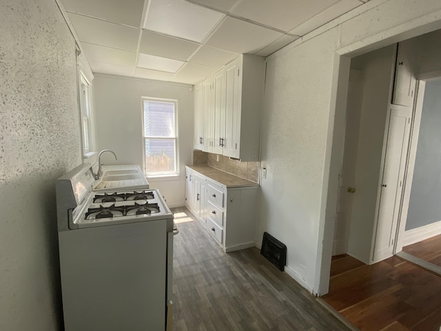 kitchen featuring a paneled ceiling, dark hardwood / wood-style flooring, sink, white cabinets, and white gas stove