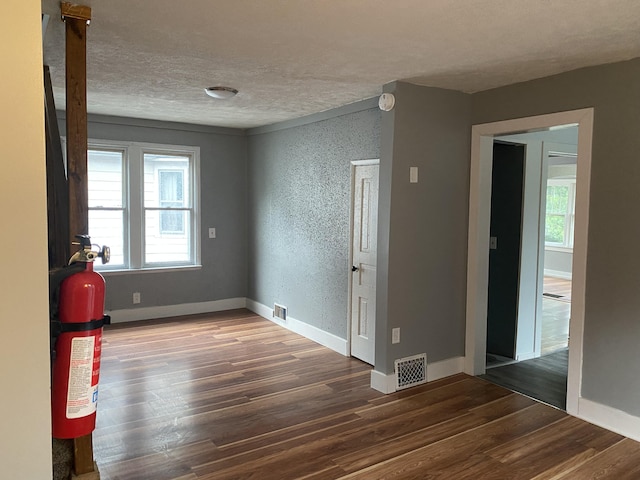 spare room with dark wood-type flooring and a textured ceiling