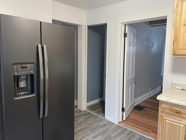 kitchen featuring light brown cabinetry, stainless steel refrigerator with ice dispenser, and hardwood / wood-style flooring