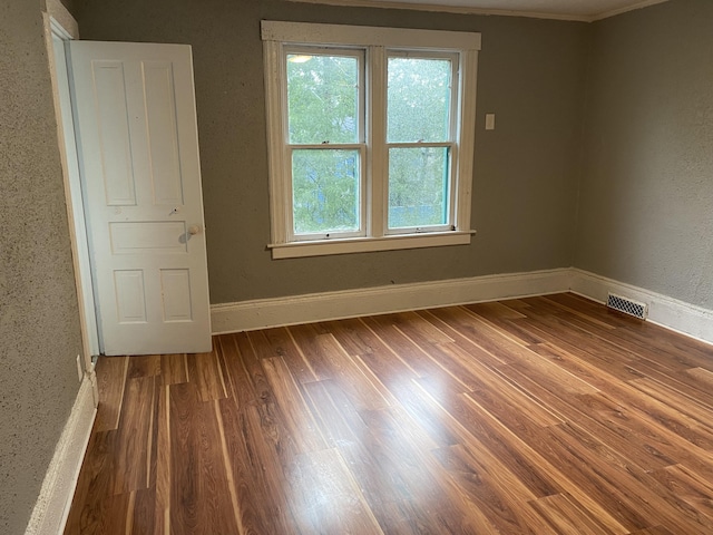 unfurnished room featuring wood-type flooring and crown molding