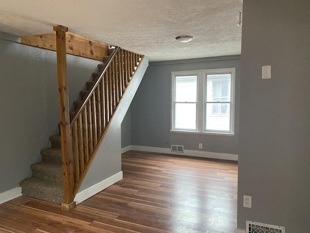 stairs with hardwood / wood-style floors and a textured ceiling